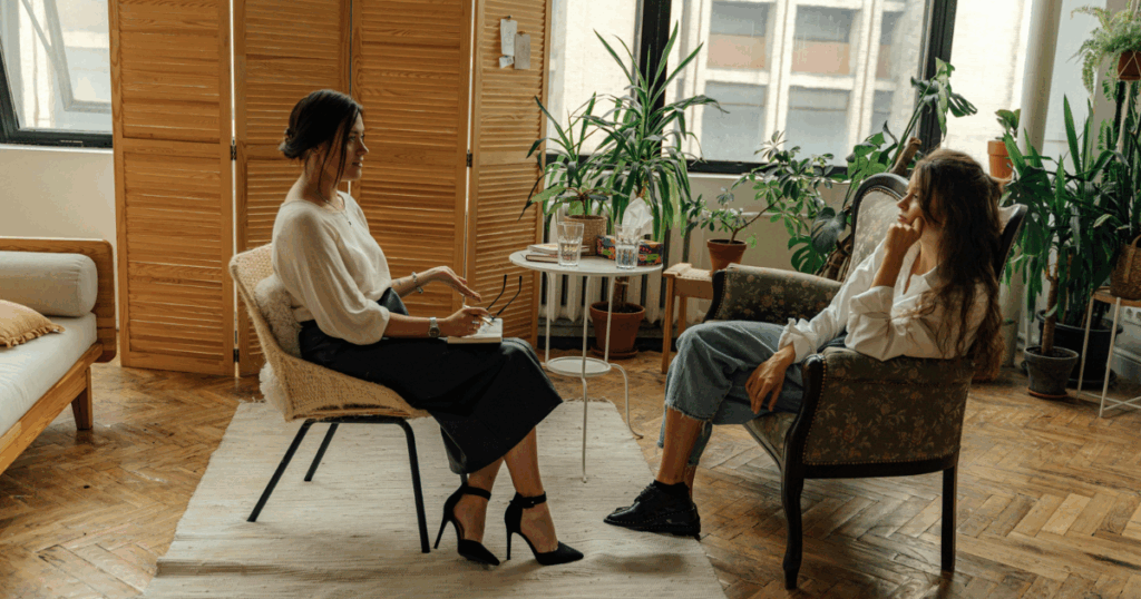 Depression therapy session: Therapist listens to patient, addressing unspecified depressive disorder in a calm, plant-filled office.