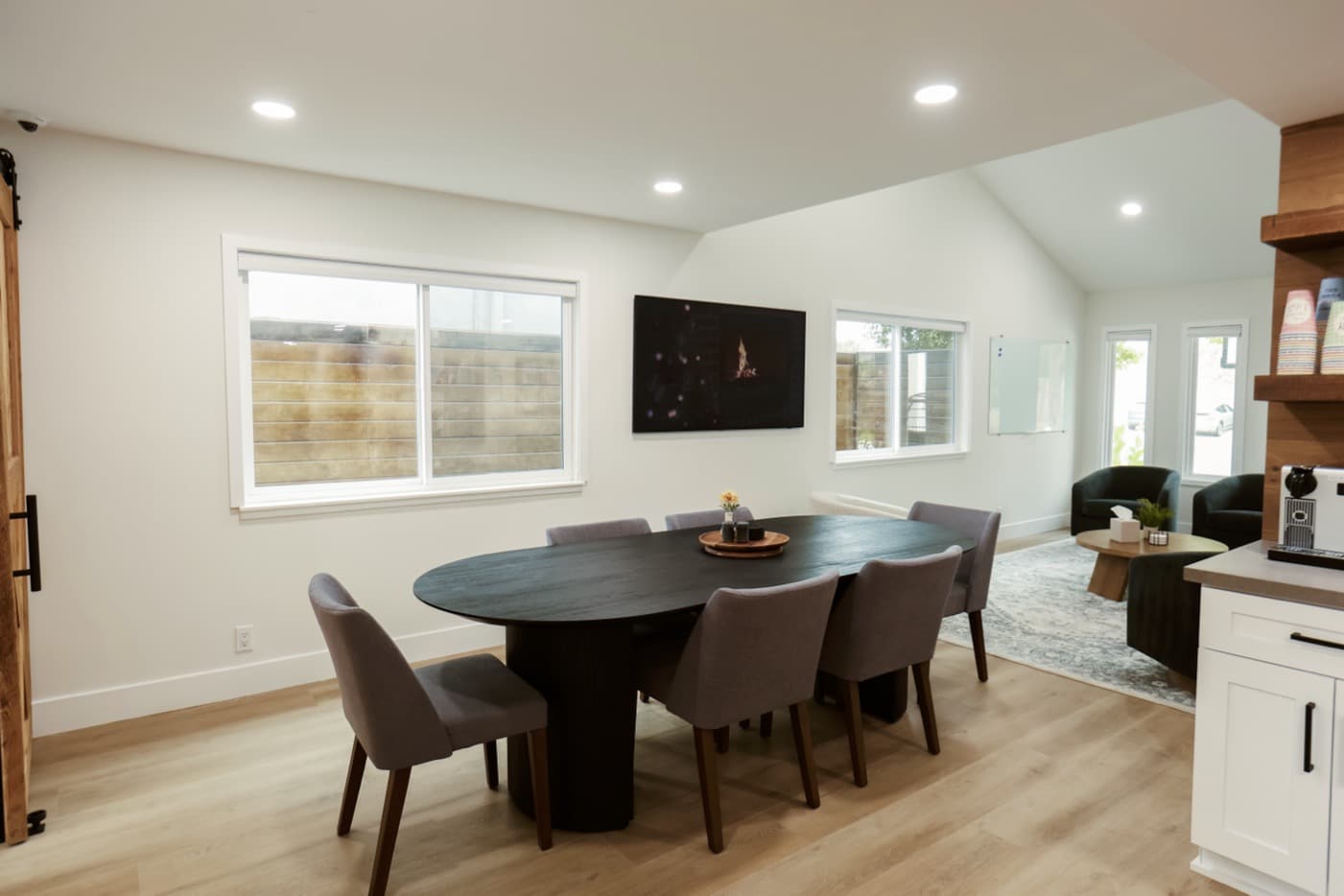 CariHouse1JaredSislinPhoto-6-copyjpg - Lonestar Mental Health Modern office interior with oval conference table, gray chairs, and bright, open workspace. CariHouse meeting space.