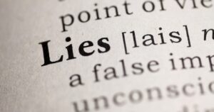 Close-up of a dictionary page highlighting the word "Lies," suggesting misinformation or falsehood (implies deception).